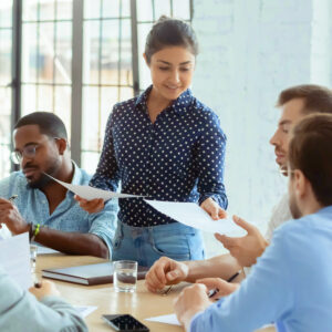 Young professional handing out documents during a team meeting in a modern office