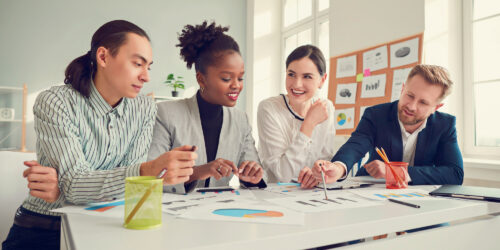 Team of professionals analyzing charts and graphs together at a conference table in a bright office