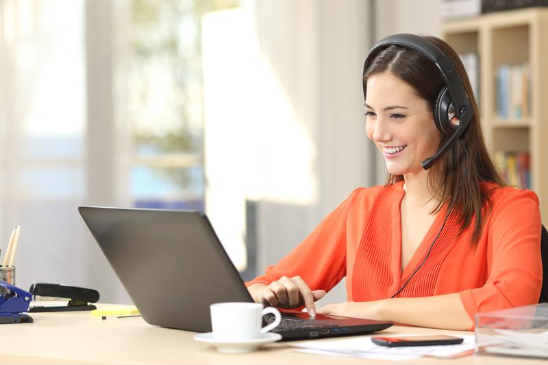 A woman sits at a desk, using her laptop computer to engage in a virtual interview.
