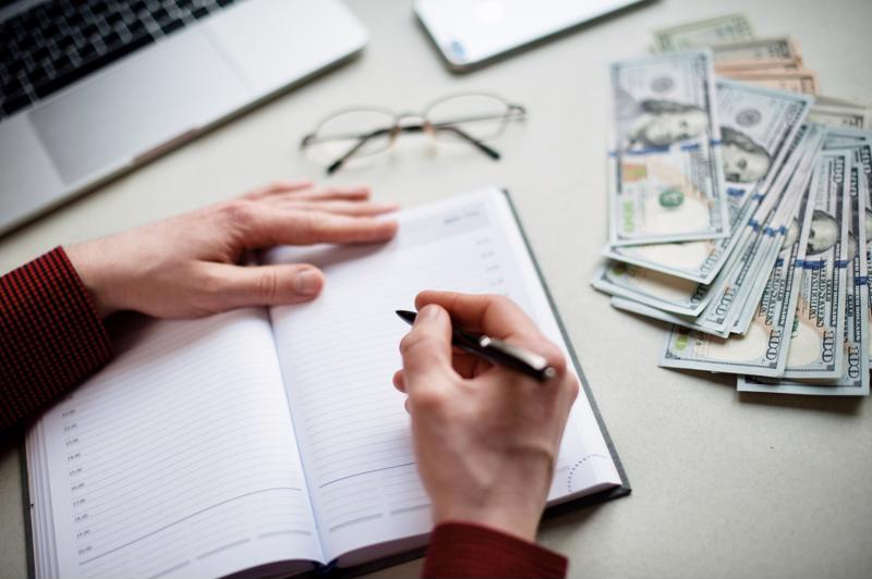 A close up of a person making a financial plan while sitting at a desk.