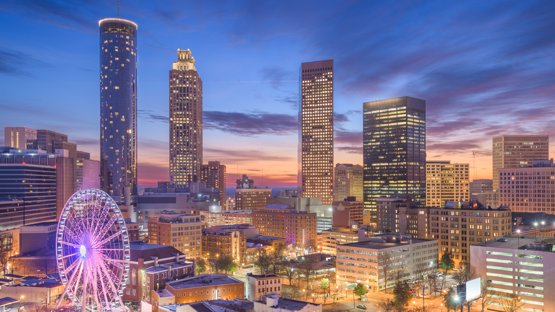 Atlanta skyline at sunset with glowing Ferris wheel and modern skyscrapers, symbolizing professional services and temp staffing and consulting in Alpharetta.