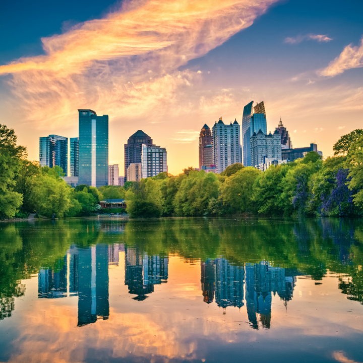 Sunset over the Atlanta-Dunwoody skyline with modern high-rises reflected in a peaceful lake, surrounded by lush greenery—symbolizing top-tier temp staffing and consulting in Dunwoody.