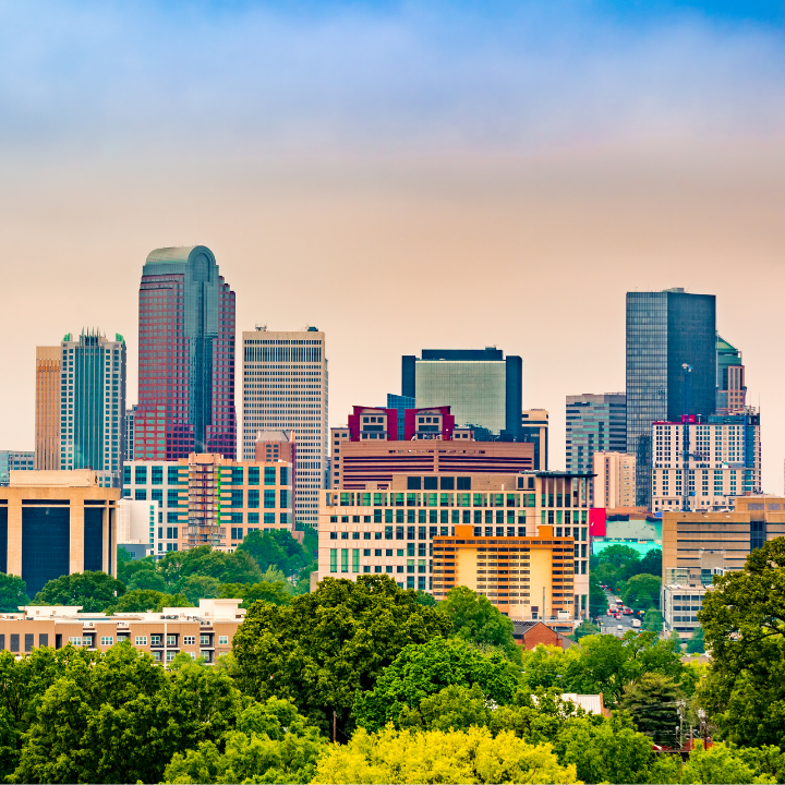 A colorful view of the Charlotte, NC skyline with modern skyscrapers rising above lush greenery, representing the city’s thriving business community and the presence of Charlotte’s leading temporary staffing and consulting services.