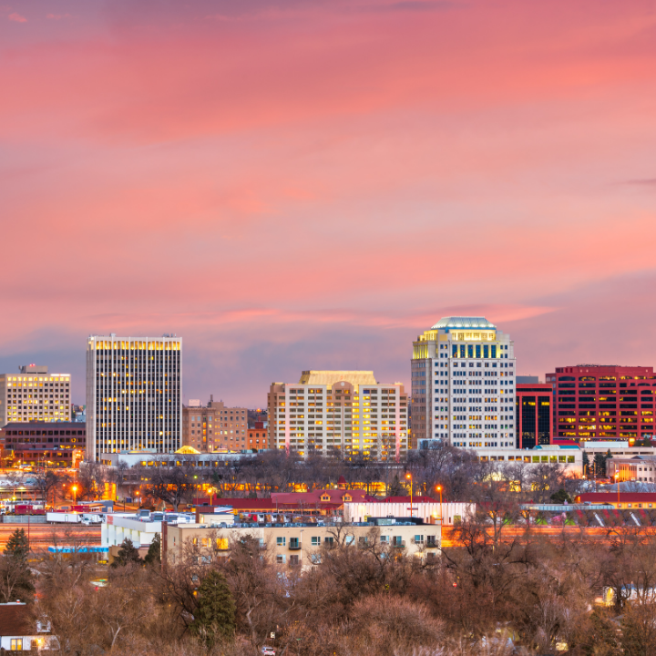 A warm sunset view over downtown Colorado Springs, featuring a mix of modern buildings and mountain foothills in the distance—representing the region supported by temp staffing and consulting services.