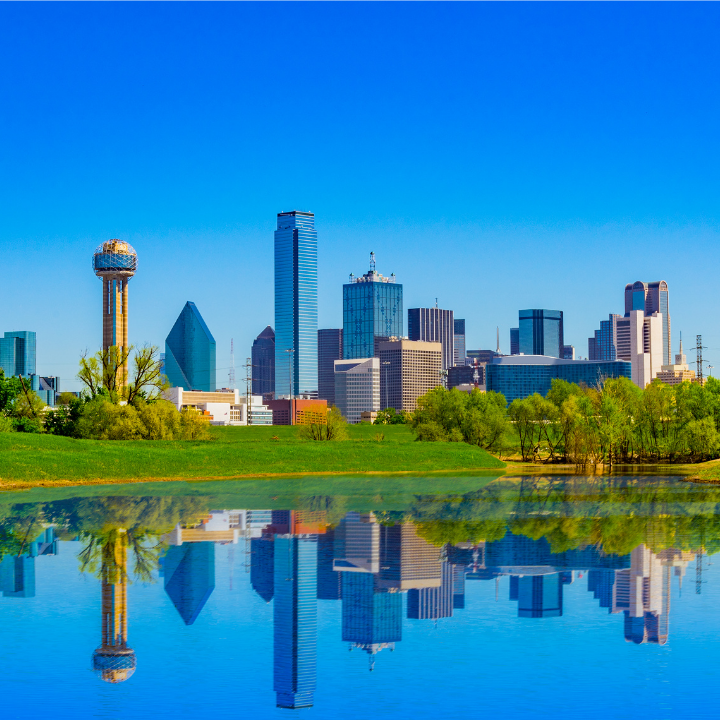 Dallas, Texas skyline with iconic buildings and clear reflections in the Trinity River on a sunny day.