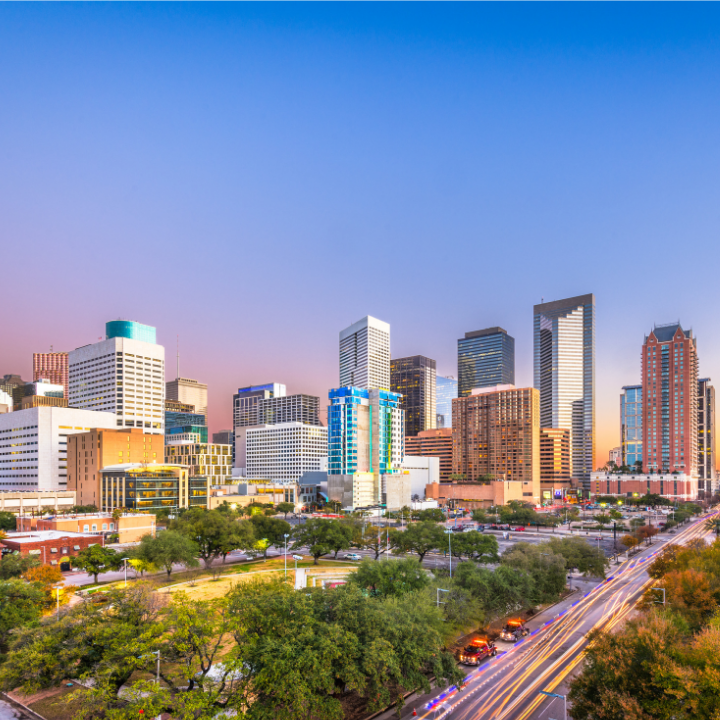 Downtown Houston skyline at dusk with modern high-rise buildings and a colorful sunset sky.