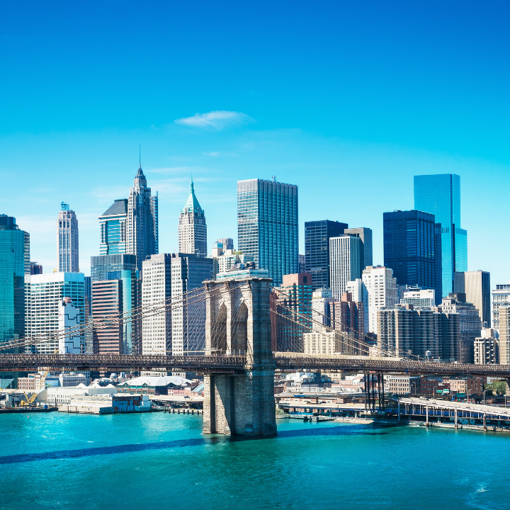 Daytime view of the Brooklyn Bridge stretching over the East River with the Manhattan skyline in the background, representing New York City’s business hub and the home of top temp NYC staffing and consulting experts.