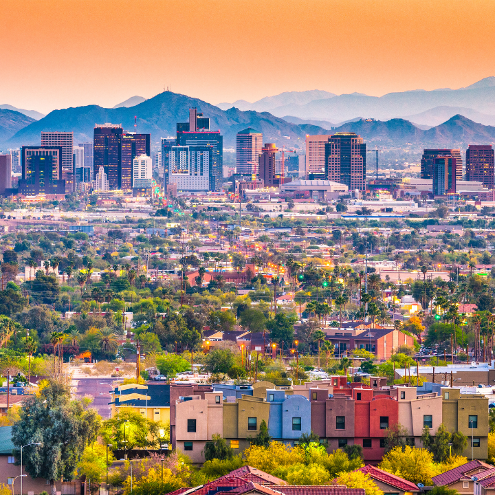 A colorful sunset view of downtown Phoenix, Arizona, with mountain backdrops, palm-lined neighborhoods, and glowing city lights—capturing the region served by top temp staffing and consulting providers.