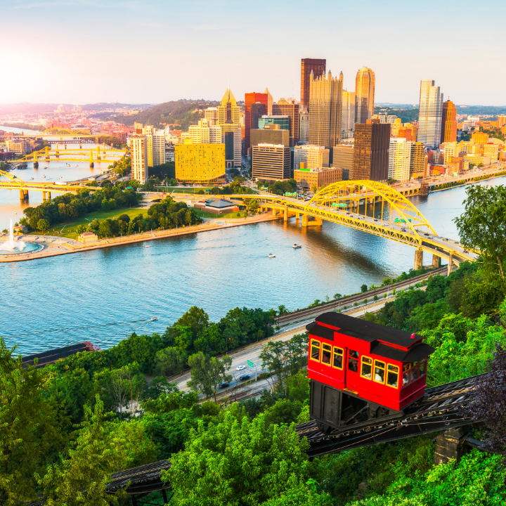 A panoramic view of downtown Pittsburgh with the Duquesne Incline in the foreground, yellow bridges spanning the rivers, and a sunlit skyline—representing the city’s role in temp staffing and consulting solutions.