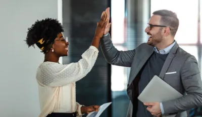 Two professionals high-five in the office after discussing the benefits of hiring a managed service provider (MSP)