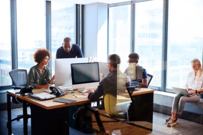 Office team working together with multiple computer monitors, representing decision-making around MSP and VMS solutions for contingent workforce management